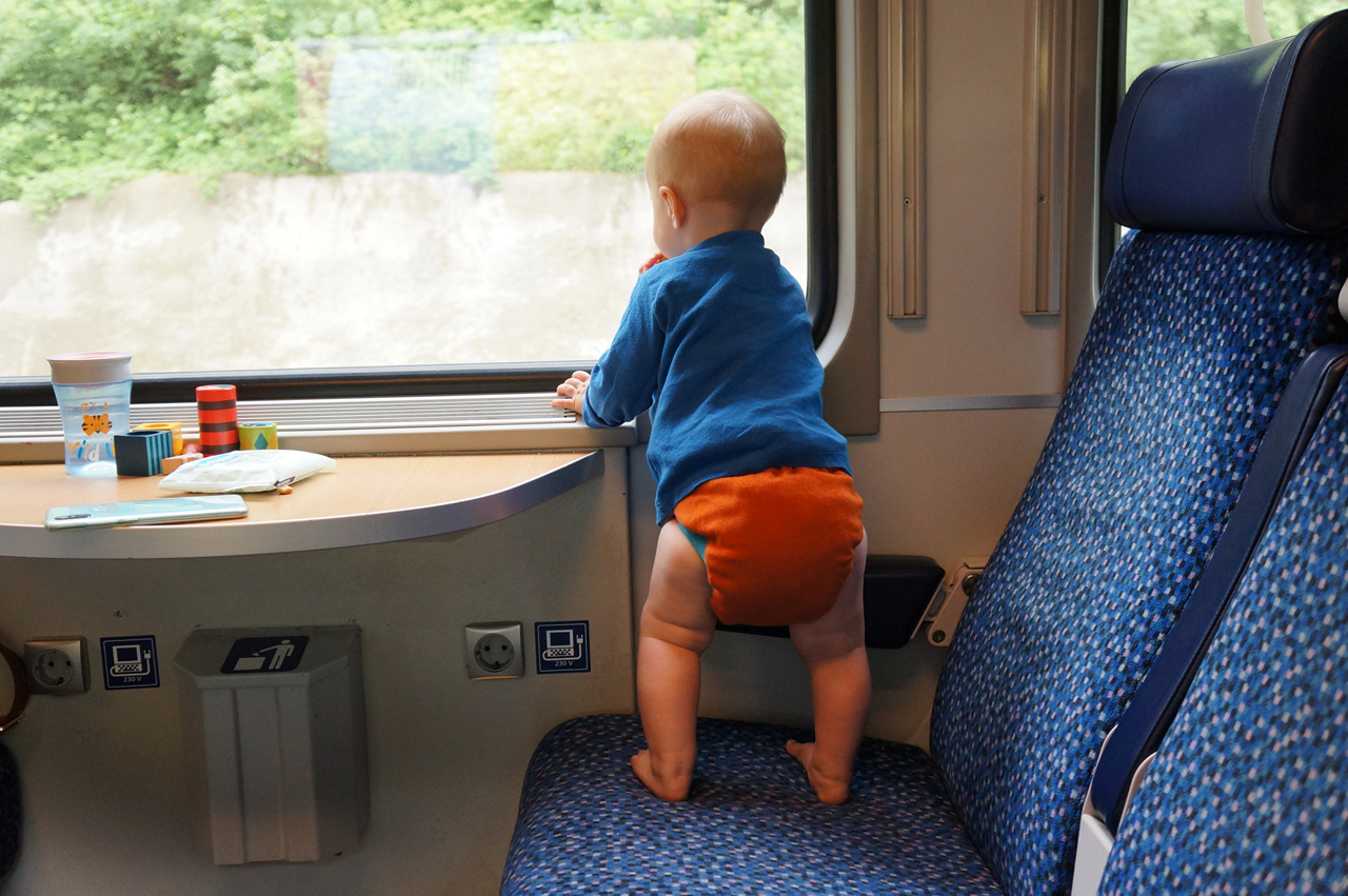 Baby mit Stoffwindel der Windelmanufaktur schaut aus dem Zug Fenster der Deutschen Bahn