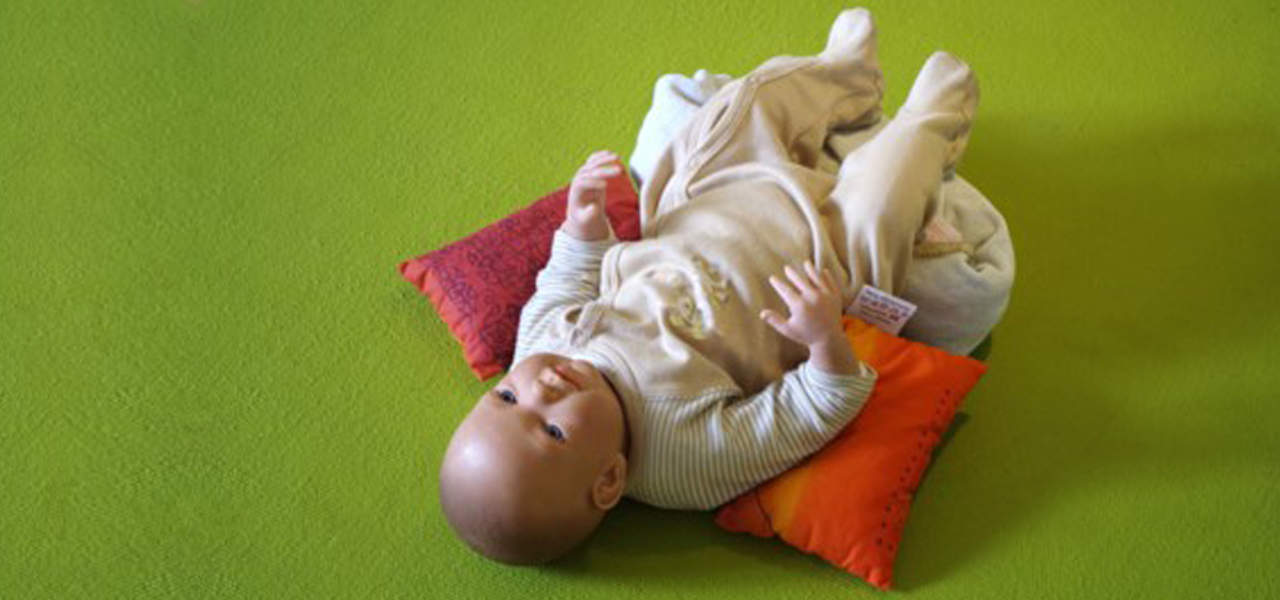 Babyhaltung im Liegen wird mit Kissen unterstützt